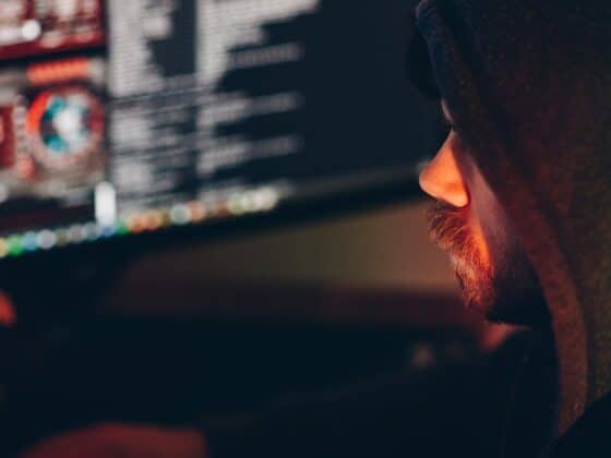 crop male hacker watching desktop computer in darkness