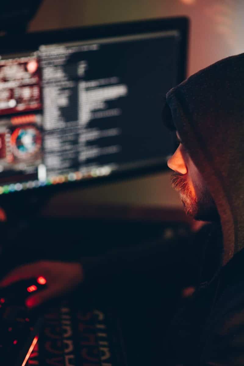 crop male hacker watching desktop computer in darkness
