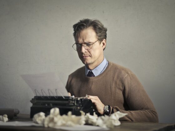 adult frowned male writer working on typewriter at home
