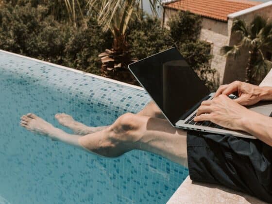 crop photo of man using black laptop computer on swimming pool