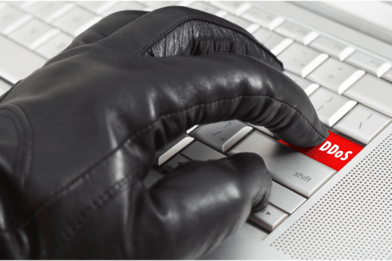 Un clavier avec une touche DDOS et un gant noir qui s'apprête à appuyer dessus