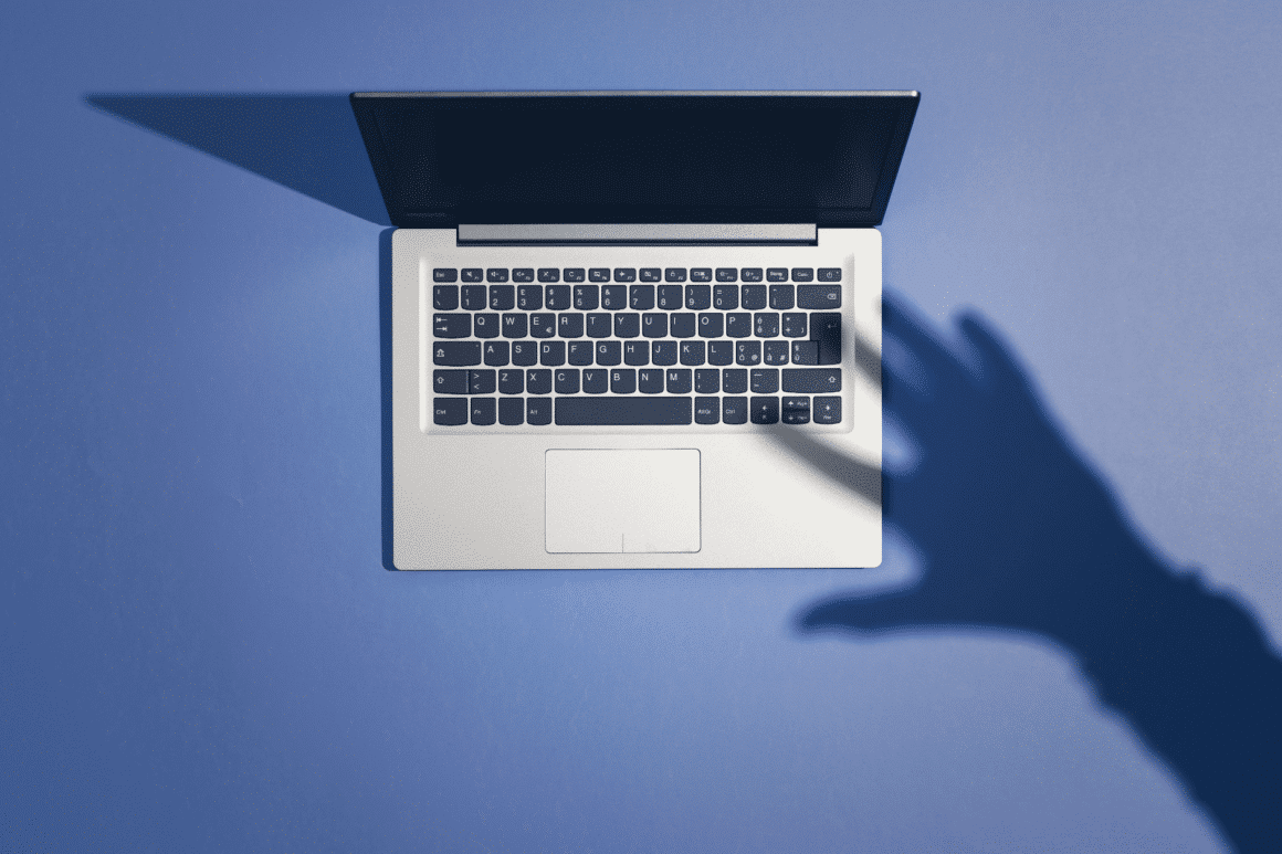 Un laptop avec l'ombre d'une main sur son clavier