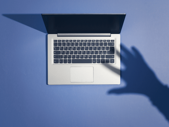 Un laptop avec l'ombre d'une main sur son clavier