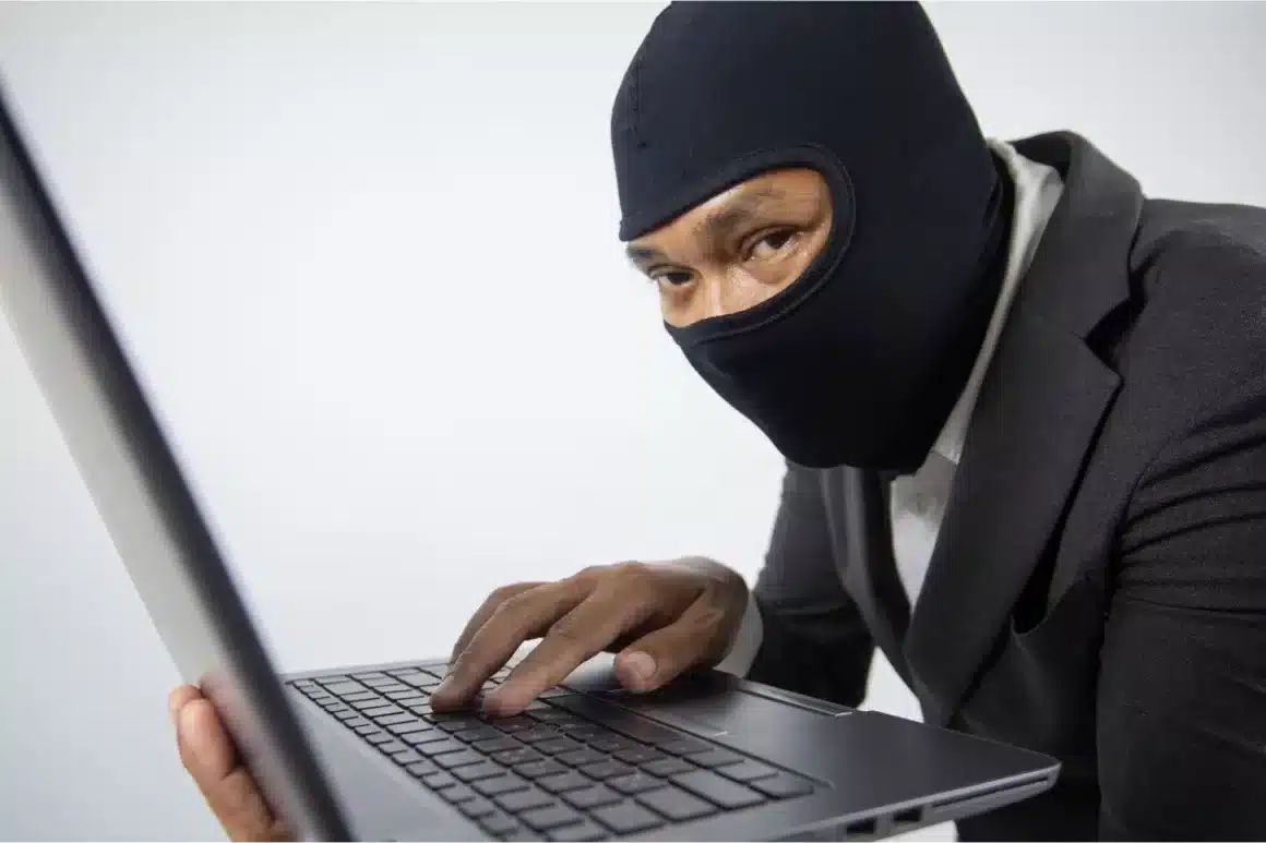 Un voleur de donnée avec une cagoule et un laptop
