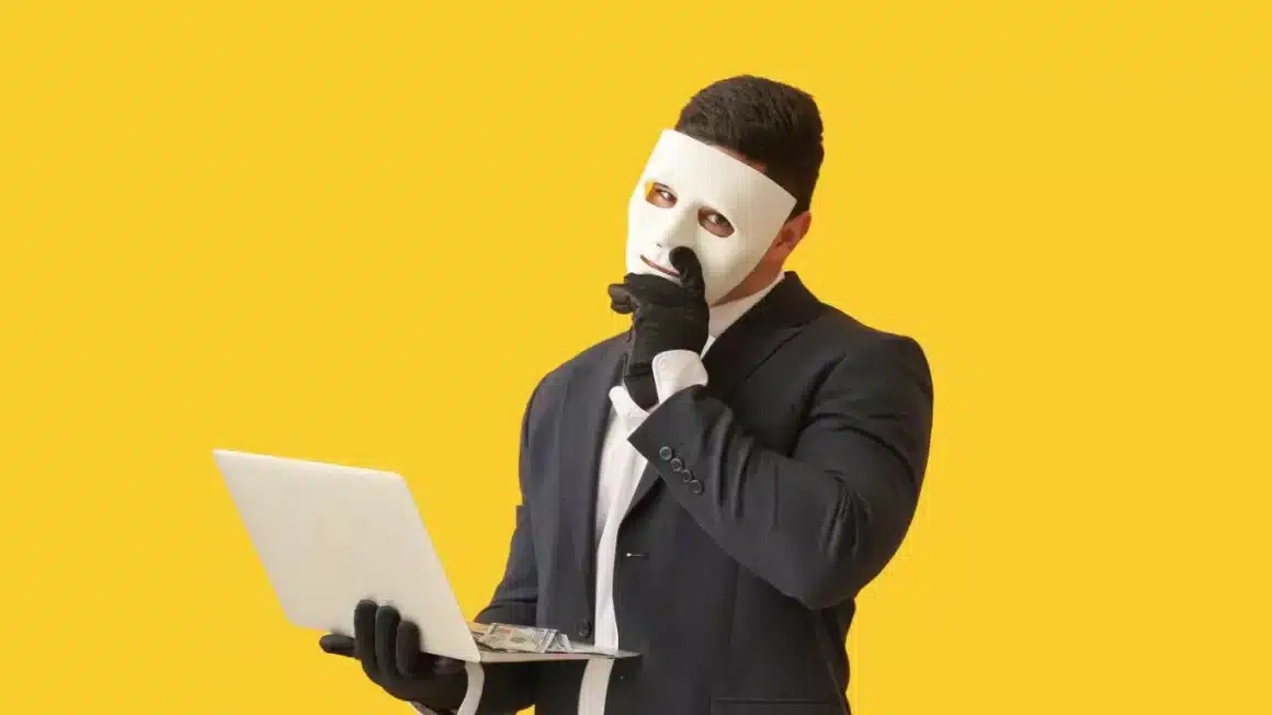 Hacker avec un masque et un ordinateur portable sur fond de couleur jaune