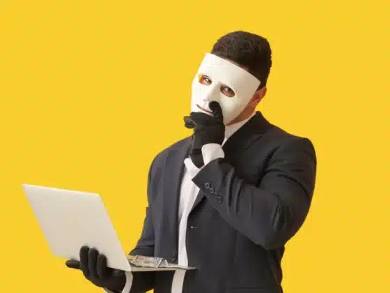 Hacker avec un masque et un ordinateur portable sur fond de couleur jaune