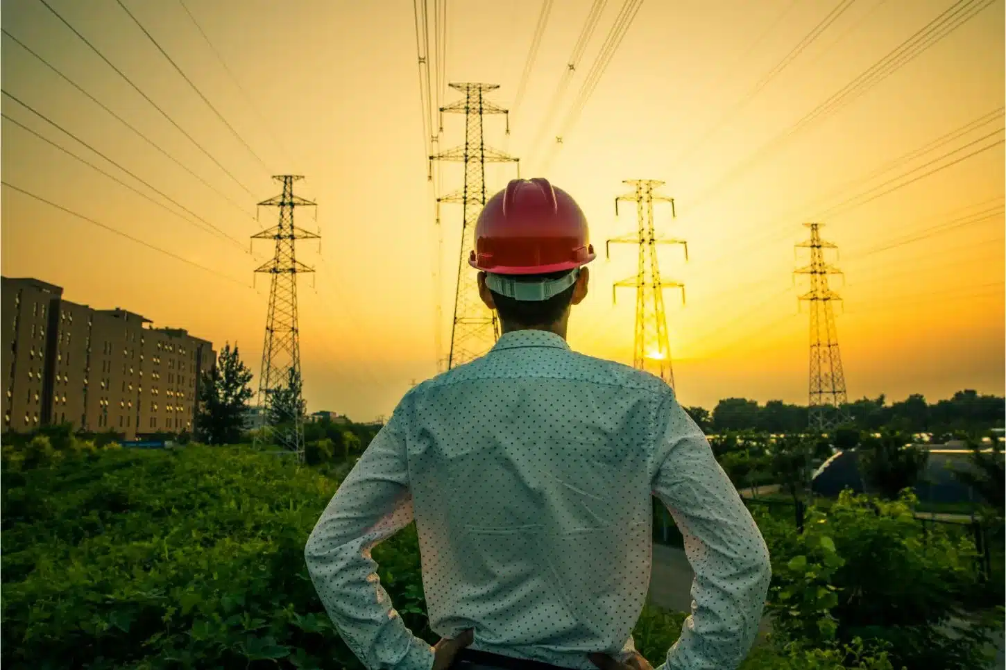 Un ingénieur de dos et regardant des lignes électriques à haute tension