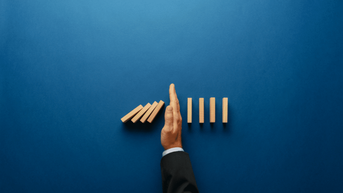 Une main qui bloque la chute de dominos