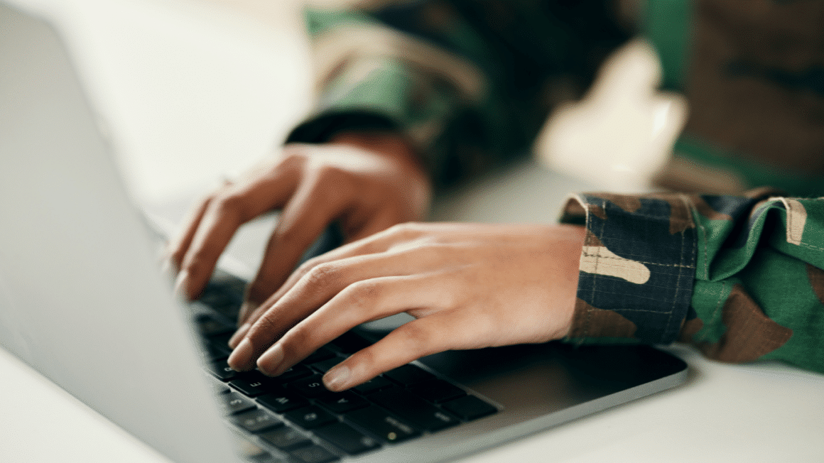 Les mains dun militaires en uniforme sur un clavier de laptop