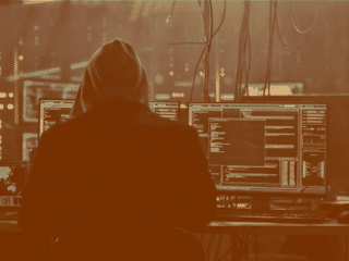 Un hacker préparant une cyberattaque devant plusieurs écrans d'ordinateur