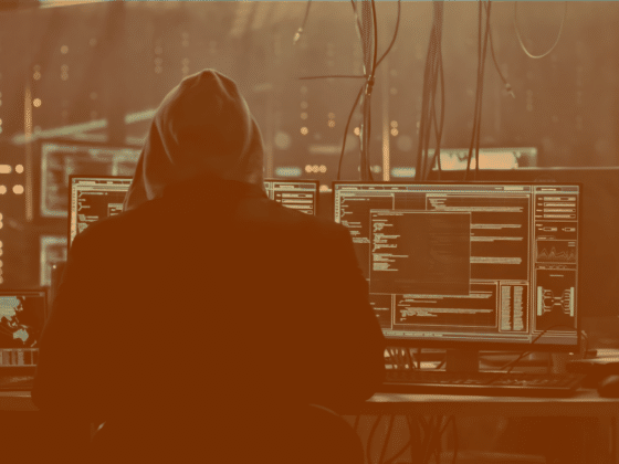 Un hacker préparant une cyberattaque devant plusieurs écrans d'ordinateur
