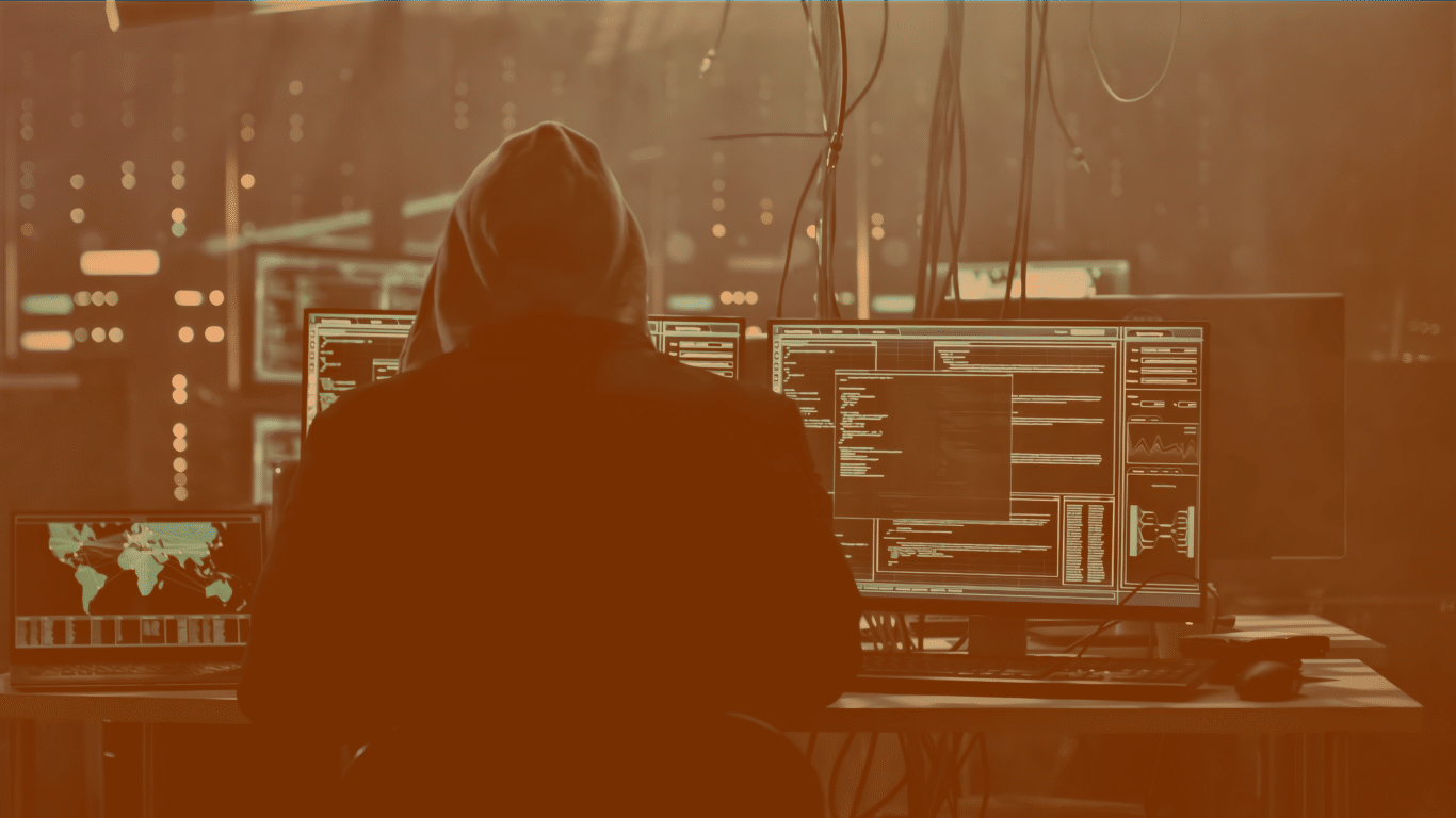 Un hacker préparant une cyberattaque devant plusieurs écrans d'ordinateur
