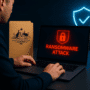 Illustration d’une attaque par rançongiciel en entreprise avec écran d’ordinateur affichant une alerte, dossier officiel australien et symbole de cybersécurité.