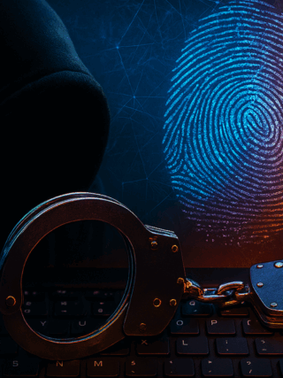 Image symbolique d'une cybercriminalité, montrant une silhouette encapuchonnée derrière un clavier d’ordinateur, des menottes métalliques posées sur les touches, et une empreinte digitale numérique lumineuse en arrière-plan sur fond de réseau digital orange et bleu. L’image évoque le piratage informatique, les arrestations de cybercriminels et l’identification numérique.