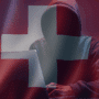 Silhouette encapuchonnée devant un ordinateur portable, symbolisant une cybermenace, sur fond de drapeau suisse translucide et ambiance sombre — évoquant les enjeux de cybersécurité en Suisse