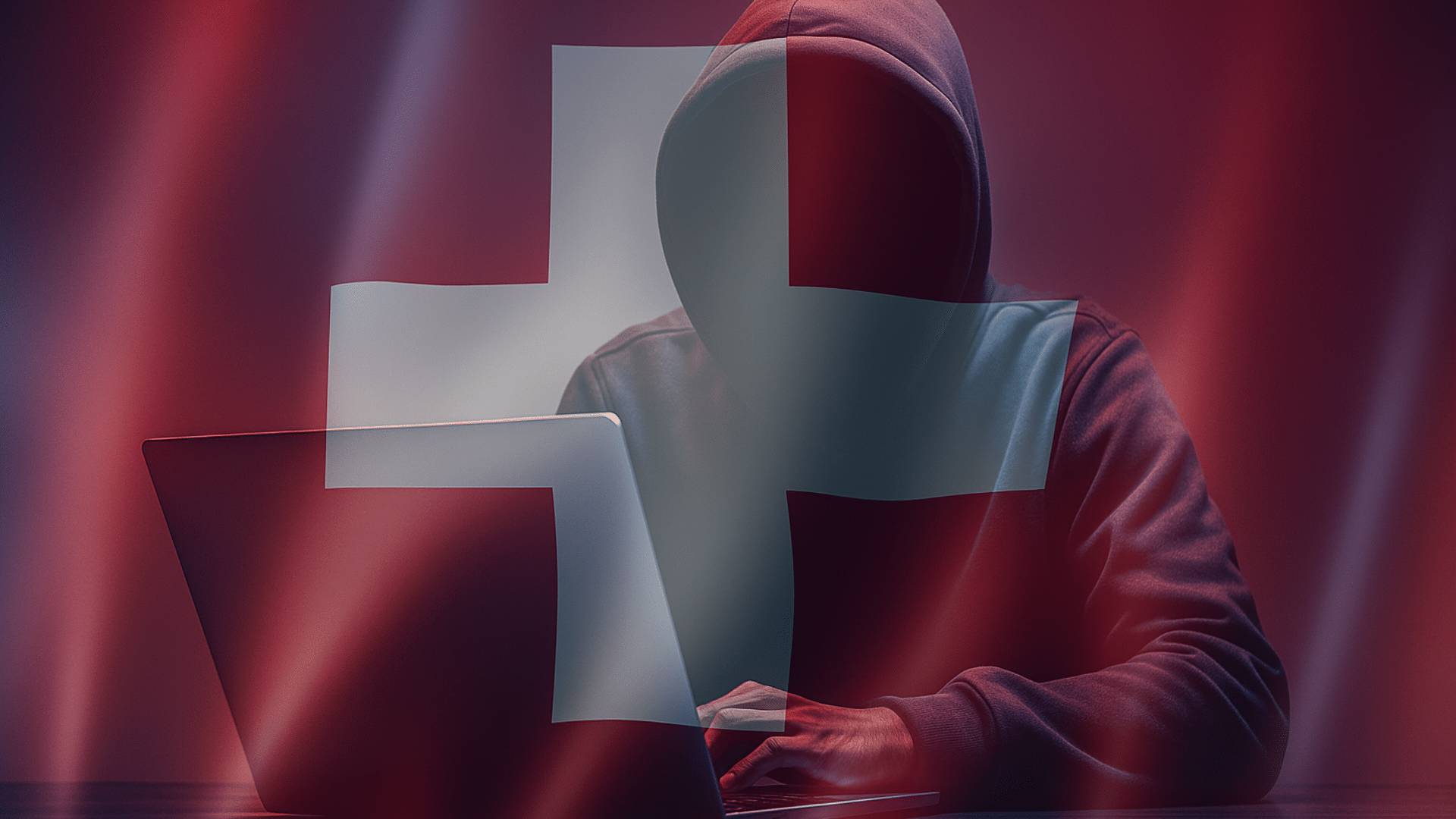 Silhouette encapuchonnée devant un ordinateur portable, symbolisant une cybermenace, sur fond de drapeau suisse translucide et ambiance sombre — évoquant les enjeux de cybersécurité en Suisse