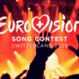 Scène de concert enflammée avec un public en liesse sous des lumières rouges et orange, illustrant le Eurovision Song Contest 2025 en Suisse. Le logo officiel du concours est au centre de l’image.