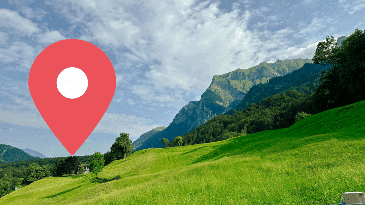 Vue panoramique d’un paysage verdoyant dans les Alpes suisses, avec un pic montagneux en arrière-plan et une icône de géolocalisation rouge au premier plan — illustration d’un test de géolocalisation assistée par intelligence artificielle.