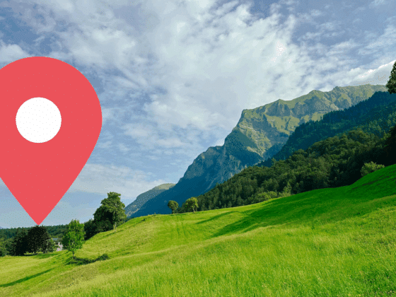 Vue panoramique d’un paysage verdoyant dans les Alpes suisses, avec un pic montagneux en arrière-plan et une icône de géolocalisation rouge au premier plan — illustration d’un test de géolocalisation assistée par intelligence artificielle.