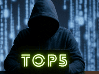 Image réaliste d'une personne encapuchonnée, assise devant un ordinateur portable dans un environnement sombre, illustrant les menaces liées au cybercrime, aux attaques informatiques et à la cybersécurité.