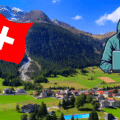 Vue d’un village alpin suisse avec un drapeau suisse et une silhouette de hacker en surimpression, illustrant les risques de cybersécurité auxquels sont confrontées les communes suisses.