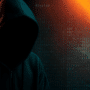 Silhouette sombre d’un individu portant une capuche, symbolisant un hacker, sur fond de code informatique et de lumières rouges et bleues, représentant une cyberattaque ou une activité de piratage.