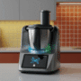 Robot de cuisine multifonction doté d’un écran tactile et d’effets lumineux numériques, posé sur un plan de travail dans une cuisine contemporaine aux tons rouges et jaunes, avec le logo « dcod » en bas à droite.