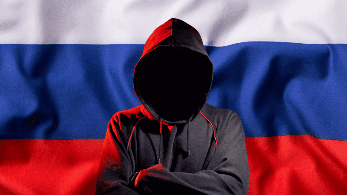 Hacker anonyme en hoodie devant un drapeau russe, représentant une menace cyber pro-russe du groupe NoName057(16)