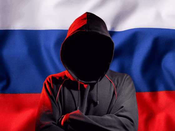 Hacker anonyme en hoodie devant un drapeau russe, représentant une menace cyber pro-russe du groupe NoName057(16)