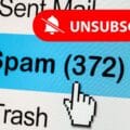 Capture d’écran d’un dossier de messagerie affichant 372 spams, avec un bouton rouge "Unsubscribe" et une icône de curseur, illustrant les risques liés aux liens de désabonnement dans les emails.