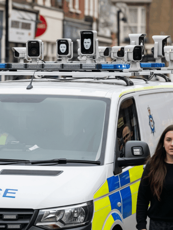 Un van de la police britannique équipé de caméras de reconnaissance faciale surveillant une foule dans une rue.