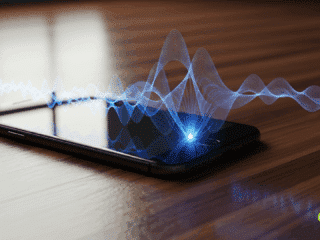 Un smartphone élégant sur une surface en bois, d'où émanent des ondes lumineuses et stylisées, symbolisant la transmission ou l'analyse des vibrations sonores.