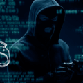 Homme masqué en hoodie, représentant un hacker, utilisant un smartphone dans un environnement numérique avec du code informatique en arrière-plan et une paire de menottes illustrée, symbolisant une arrestation.