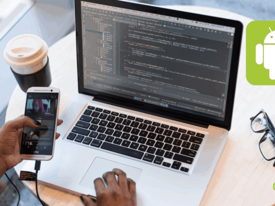 Vue rapprochée d’un développeur travaillant sur une application Android avec un ordinateur portable affichant du code Java dans Android Studio, tout en testant l’application sur un smartphone connecté via USB. Une tasse de café, une paire de lunettes et le logo Android sont visibles sur la table.