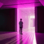 Dans un espace minimaliste en béton, un adolescent vu de dos fait face à un portail de lumière magenta. Les rayons lumineux projettent de longues ombres sur le sol poli, symbolisant un seuil ou une barrière numérique.