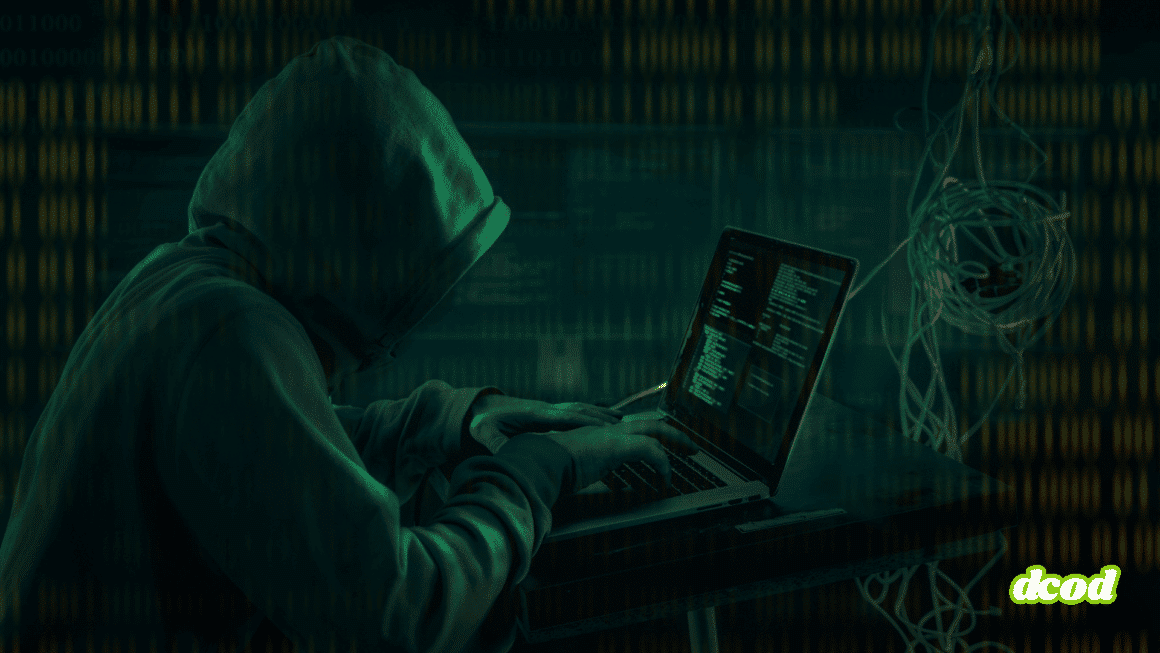 Personne portant une capuche, tapant sur un ordinateur portable dans un décor sombre, illustrant le piratage informatique ou une cyberattaque, avec des lignes de code visibles à l’écran.