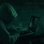 Personne portant une capuche, tapant sur un ordinateur portable dans un décor sombre, illustrant le piratage informatique ou une cyberattaque, avec des lignes de code visibles à l’écran.