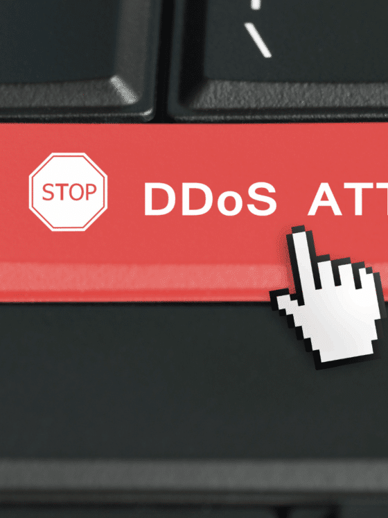 Touche rouge d’un clavier d’ordinateur portant l’inscription « STOP DDoS ATTACK » avec un curseur en forme de main, symbolisant l’interruption d’une attaque par déni de service distribué (DDoS)