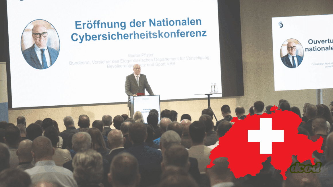 Martin Pfister, conseiller fédéral suisse, prononce le discours d’ouverture de la Conférence Nationale sur la Cybersécurité devant un public attentif, avec une carte rouge de la Suisse ornée d'une croix blanche en premier plan.