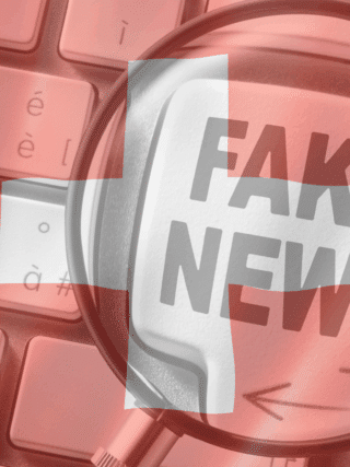 Clavier d’ordinateur avec une touche marquée « FAKE NEWS » vue à travers une loupe, surmontée d’un drapeau suisse en transparence, illustrant la problématique de la désinformation en ligne en Suisse.