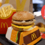 Plateau-repas McDonald's comprenant un cheeseburger, des frites, une boisson et des nuggets, avec une icône de cybersécurité brisée en surimpression, symbolisant une faille informatique ou un piratage dans le contexte de la restauration rapide.