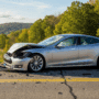 Photographie hyper-réaliste d'une Tesla Model S accidentée sur une route asphaltée, avec des débris de voiture éparpillés