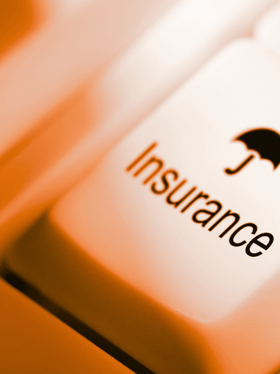 Gros plan sur une touche de clavier blanche avec l’icône d’un parapluie et le mot « Insurance », représentant l’accès aux services d’assurance en ligne.
