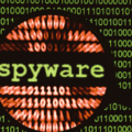 Illustration d’un écran rempli de code binaire vert avec le mot « spyware » mis en évidence par une loupe, représentant la détection de logiciels espions dans un environnement numérique.