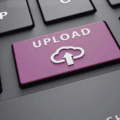 Vue rapprochée d’un clavier d’ordinateur avec une touche violette portant l’inscription « Upload » et une icône de cloud, symbolisant le téléversement de fichiers vers le cloud ou un serveur en ligne.