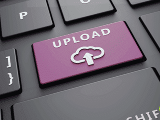 Vue rapprochée d’un clavier d’ordinateur avec une touche violette portant l’inscription « Upload » et une icône de cloud, symbolisant le téléversement de fichiers vers le cloud ou un serveur en ligne.