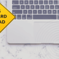 Vue partielle d’un ordinateur portable Apple sur fond en marbre, avec un panneau jaune en forme de losange affichant le message « Big reward ahead ». L’image illustre l’annonce d’Apple concernant l’augmentation des primes pour la découverte de failles zero-click. Logo « dcod » en bas à droite.