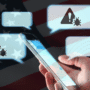 Main tenant un smartphone avec des bulles de conversation contenant des icônes d’alerte et de virus, sur fond de drapeau des États-Unis, illustrant les cyberattaques ou campagnes de désinformation via messagerie mobile.