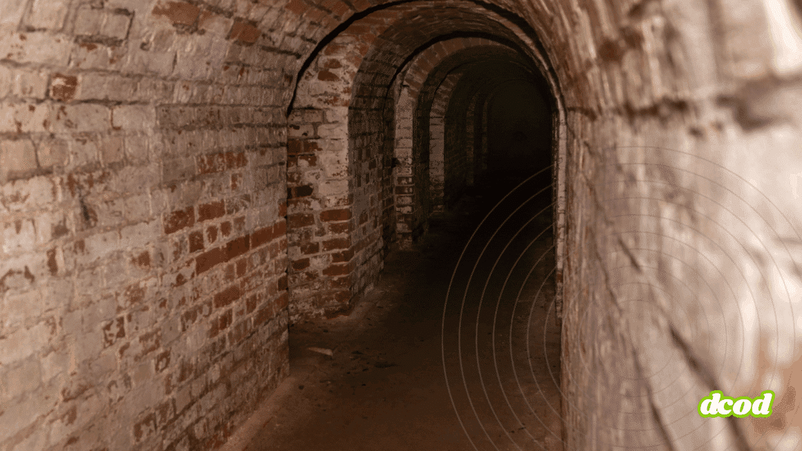 Couloir d’un ancien bunker en briques, voûté et souterrain, illustrant la transformation de structures militaires en centres de données ultra-sécurisés. L’architecture robuste et l’absence de lumière naturelle soulignent l’intérêt stratégique de ces lieux pour l’hébergement numérique. Logo « dcod » en bas à droite.