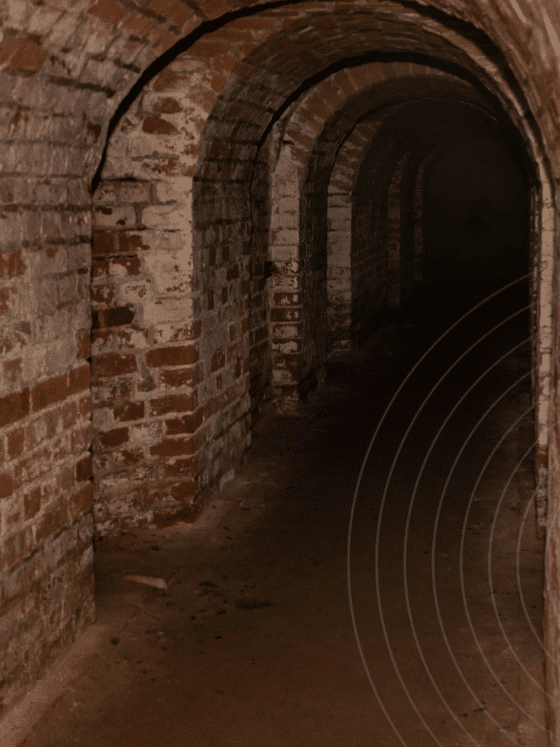 Couloir d’un ancien bunker en briques, voûté et souterrain, illustrant la transformation de structures militaires en centres de données ultra-sécurisés. L’architecture robuste et l’absence de lumière naturelle soulignent l’intérêt stratégique de ces lieux pour l’hébergement numérique. Logo « dcod » en bas à droite.
